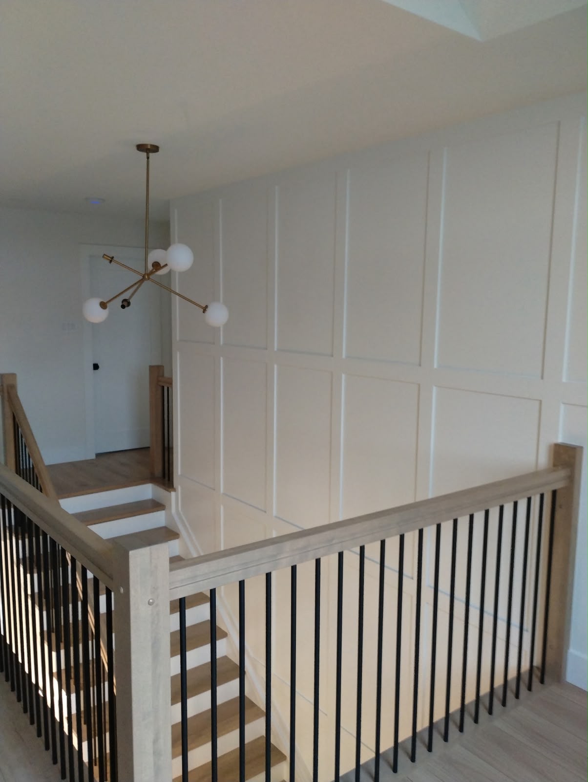 Custom wall panel trim beside hardwood staircase